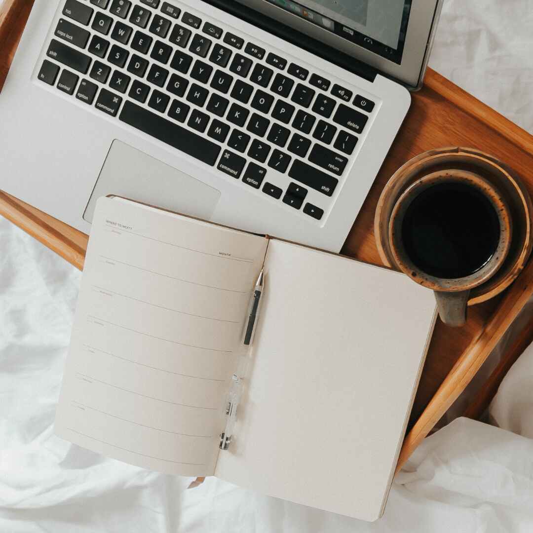 desk on bed with laptop, coffee and calendar